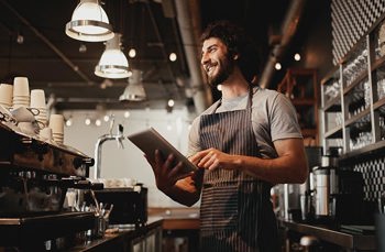 A waiter smiling holding a tablet 