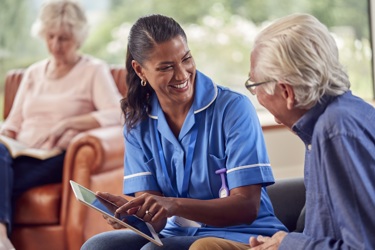 Nurse using a tablet to discuss something with an elderly man