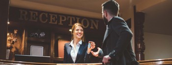 Hotel receptionist handing a key to a guest