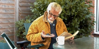 A man reading a book and looking at keys in his hands 