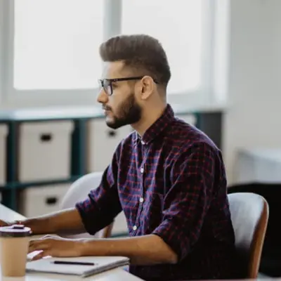 Person working at a desk with a laptop and coffee cup representing a client testimonial for Access Legal software