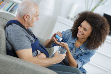 A nurse assisting an old man with his medication