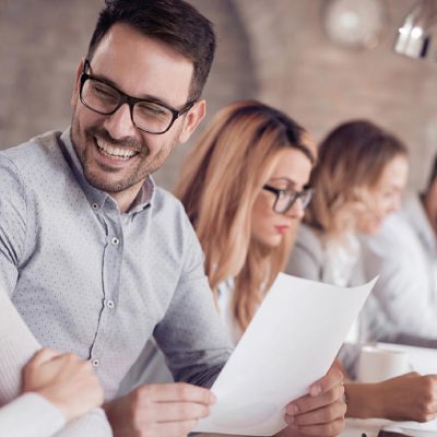 Four people sitting down and two of them looking at each other smiling 