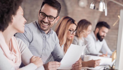 Four people sitting down and two of them looking at each other smiling