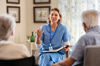 The back of an elderly couple talking to a nurse
