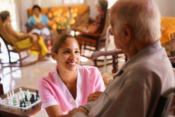 care worker sitting beside an elderly resident, checking on him