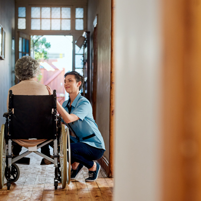 An elderly woman on a wheelchair being comforted by a female nurse 