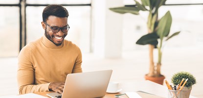A black man smiling on his laptop