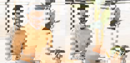 A black man smiling on his laptop