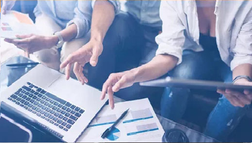  Team reviewing charts and graphs around a table with a laptop and documents