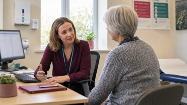A GP talking with a patient in their consultation room.