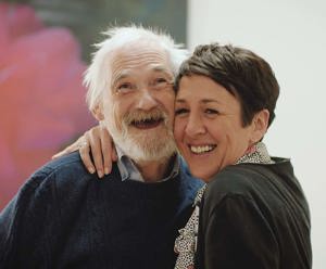 A woman hugging a smiling elderly man 