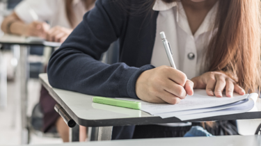 School student writing on paper during class