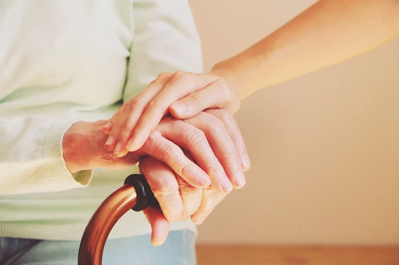 an image of a woman holding walking stick and a carer's hand to show how enhancing primary care access reduces admissions