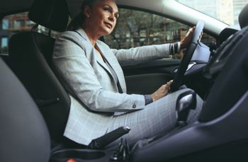 Person in a gray plaid suit driving a car