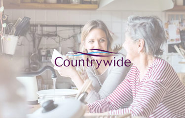 Two women chatting at a kitchen table with dishes, overlaid by the ‘Countrywide’ logo