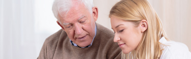 A young woman showing something to an elderly man who is looking down at it