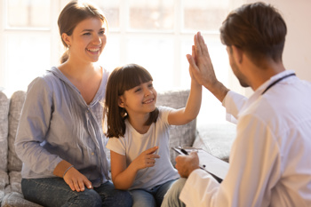 An image of a child smiling and high fiving a support worker to show children's mental health is important