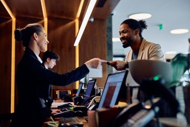 Hotel Reception Desk With Staff And Guest Interacting