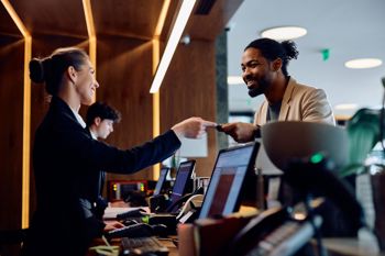Hotel Reception Desk With Staff And Guest Interacting