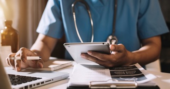 A nurse using healthcare monitoring software for a virtual ward patient.