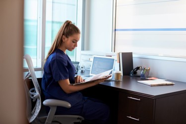 care worker sitting at a desk while checking a file