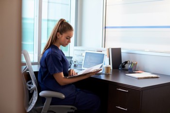 care worker sitting at a desk while checking a file