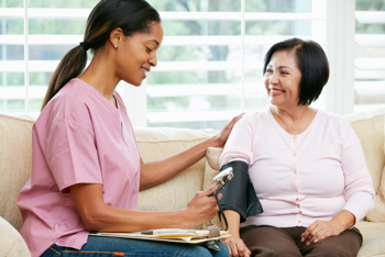Care worker taking the blood pressure of an elderly lady.