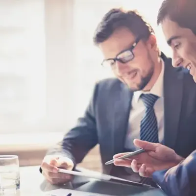 Two professionals reviewing information on a tablet during a meeting