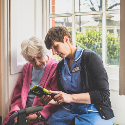 A nurse showing an elderly lady something on a tablet