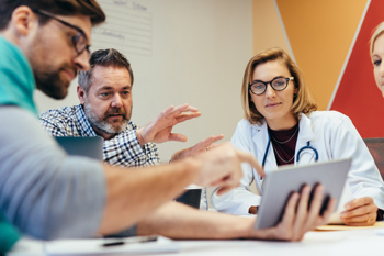 Clinicians and management in a hospital meeting.