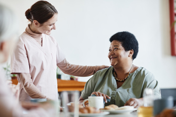 care worker checking on elderly resident while the resident has their meal